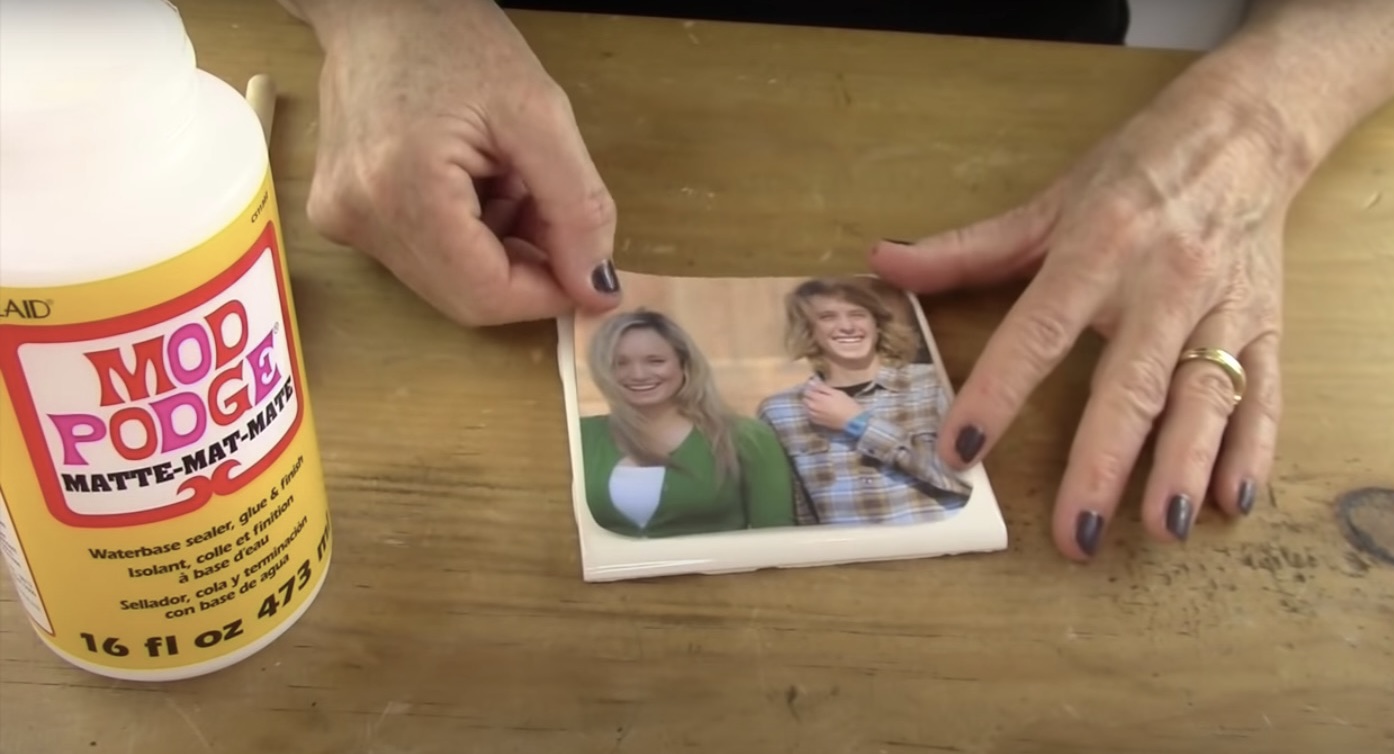 This shows how to adhere photos of loved ones to ceramic tiles with modpodge on the on the DIY Photo coaster project.