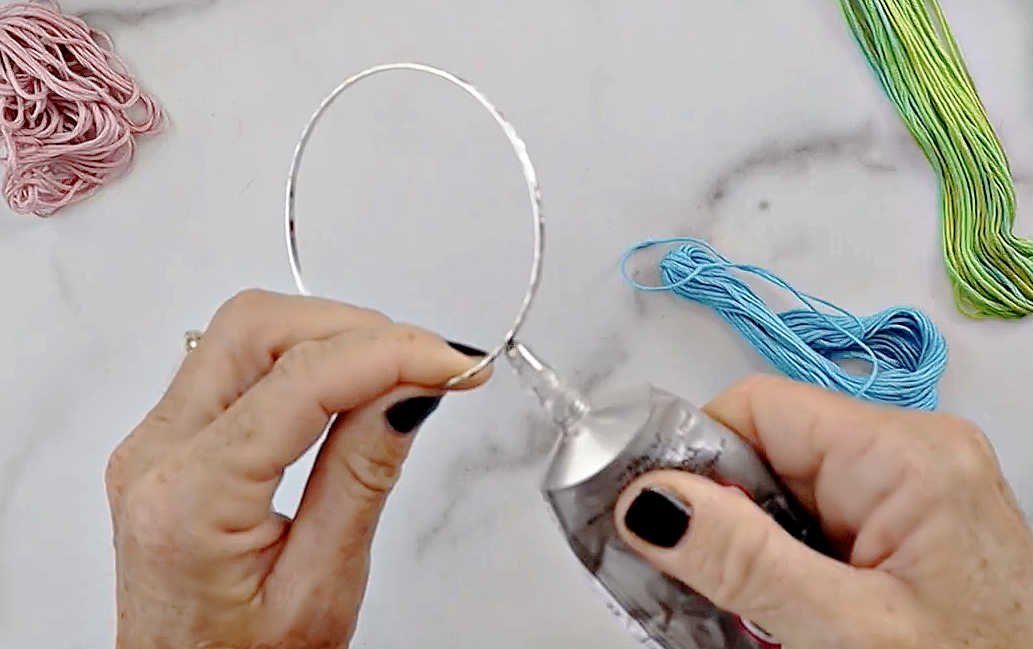 This is a DIY Bracelet tutorial to make bracelets using embroidery thread. This is the first step in the process.  Glue the end of your embroidery floss to the silver bangle bracelet.
