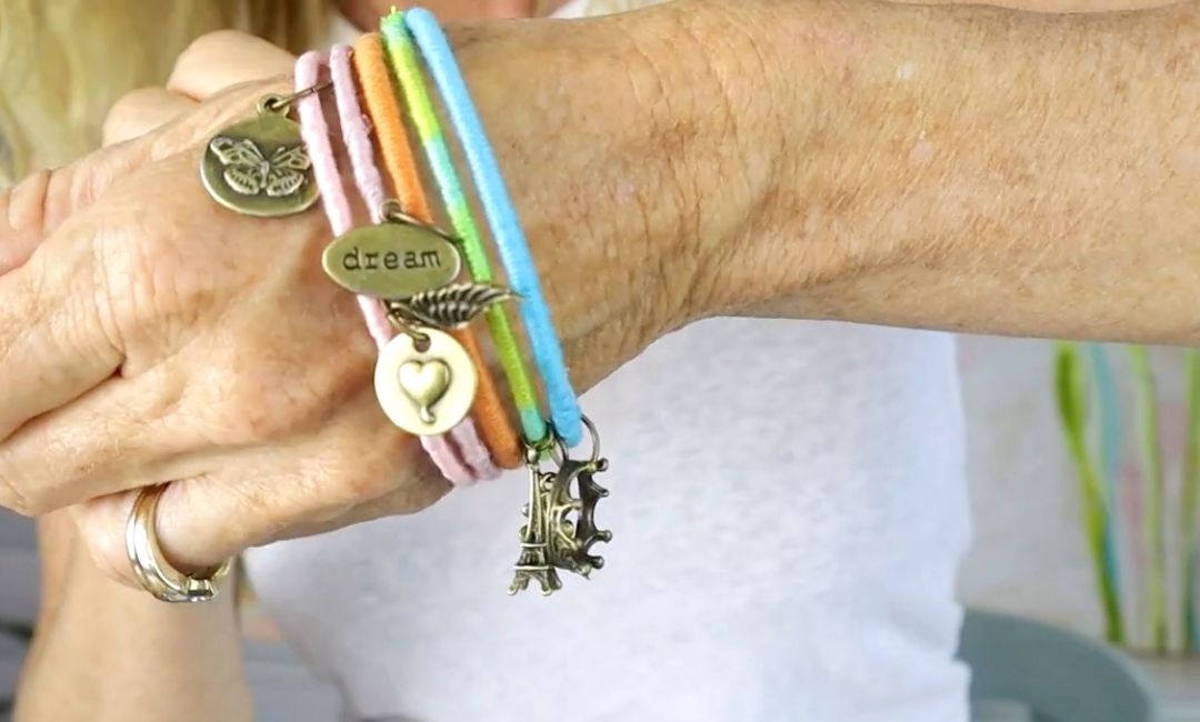 A stack of DIY charms bracelets on a wrist.